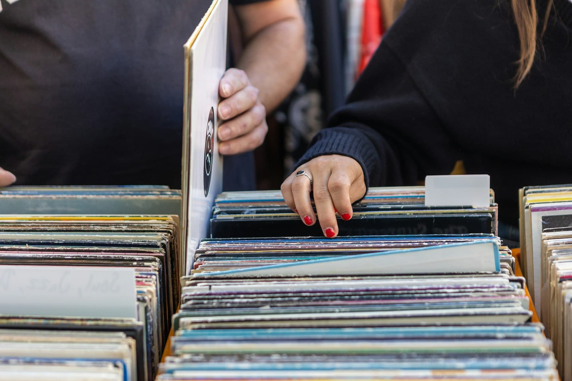 Hands flipping through crates of vinyl records in a record shop