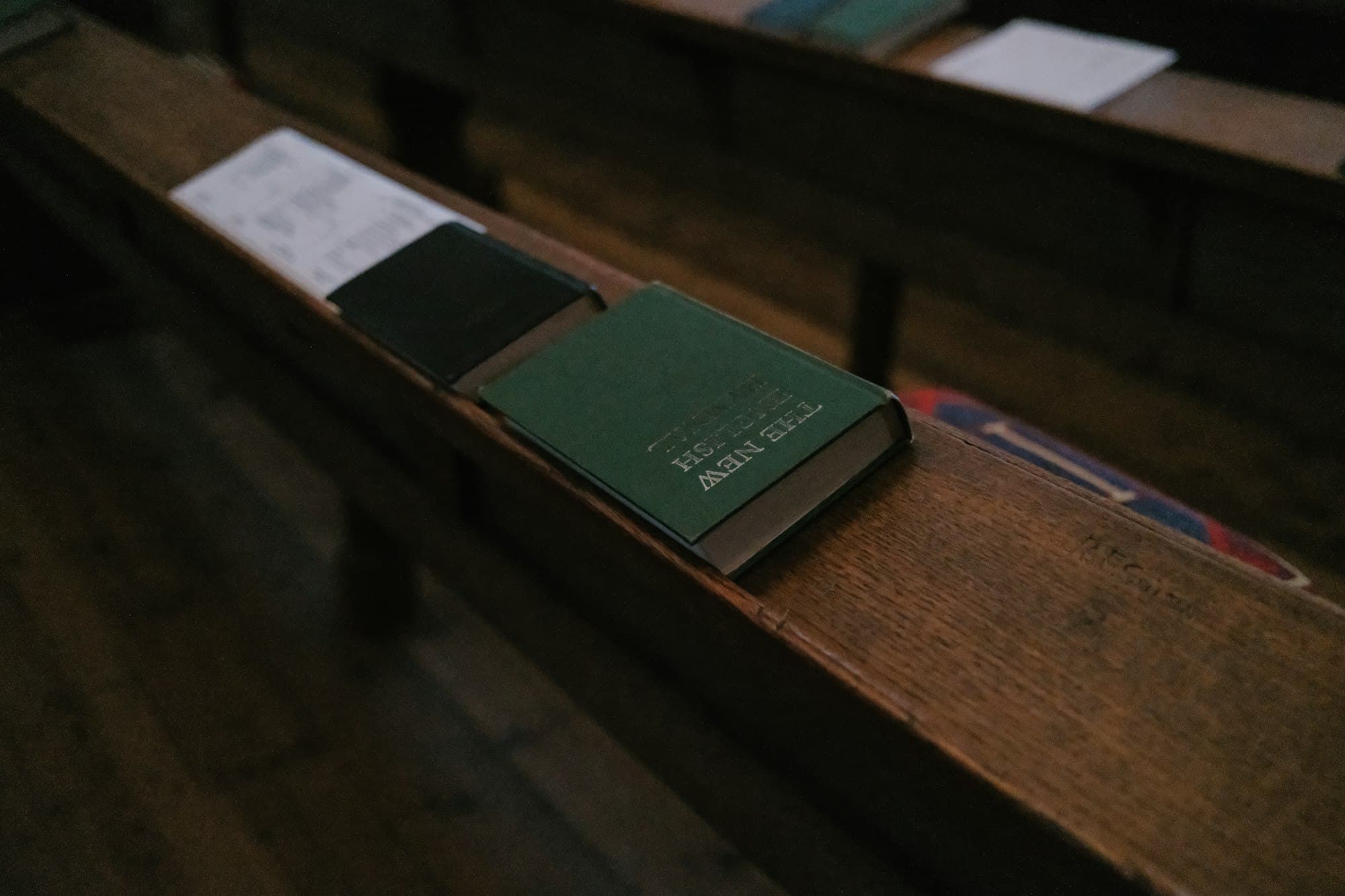 Closed books resting on a dark wooden church pew