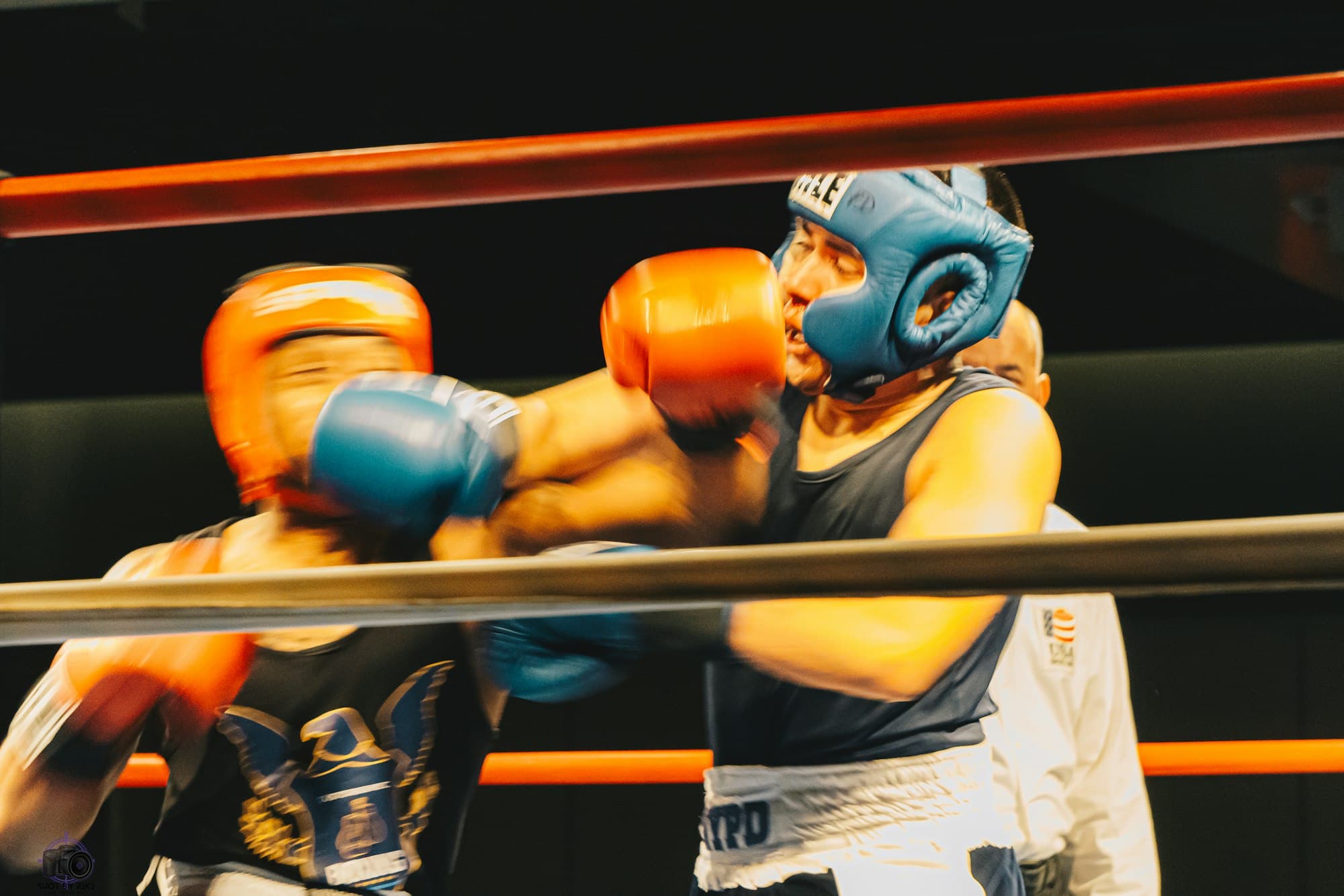 Two boxers in headgear trade punches inside a ring