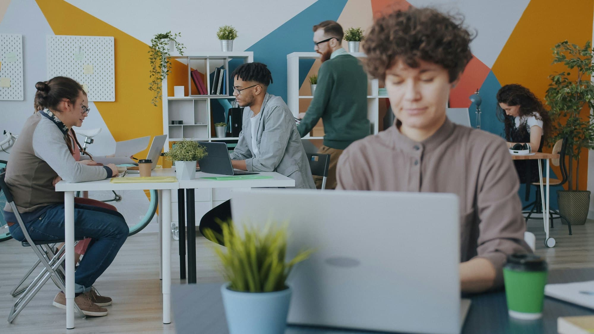 People working on laptops at desks in a bright, colorful open-plan office