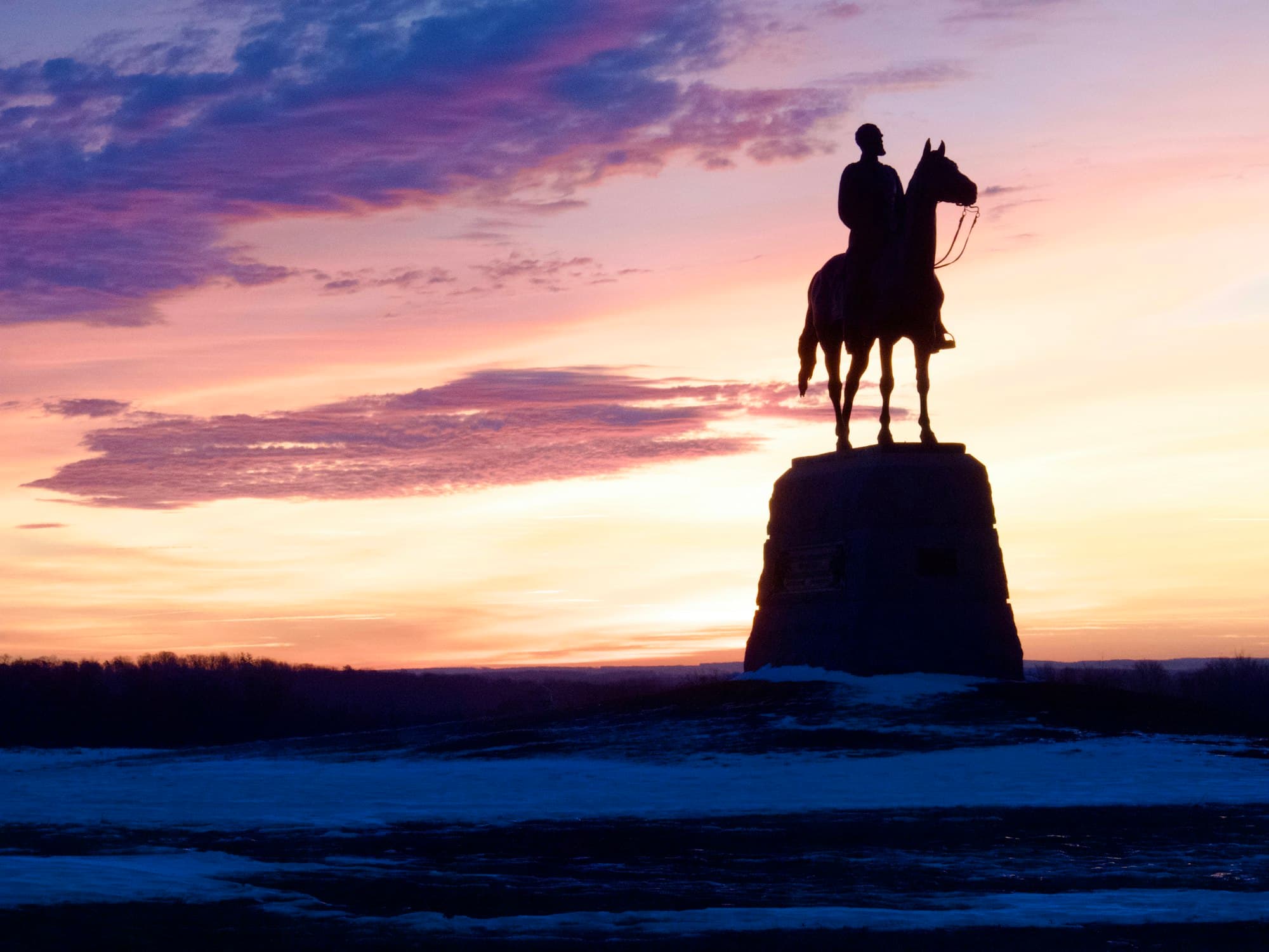 A silhouetted equestrian monument against a purple and orange sunset at Gettysburg