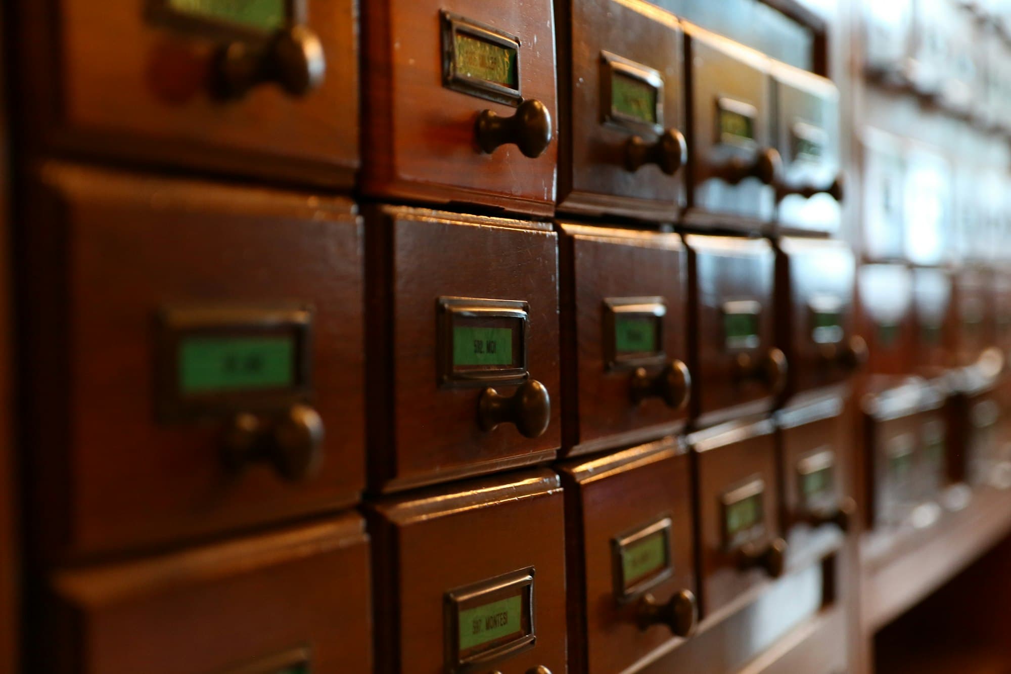 Rows of vintage wooden card-catalog drawers in dim light