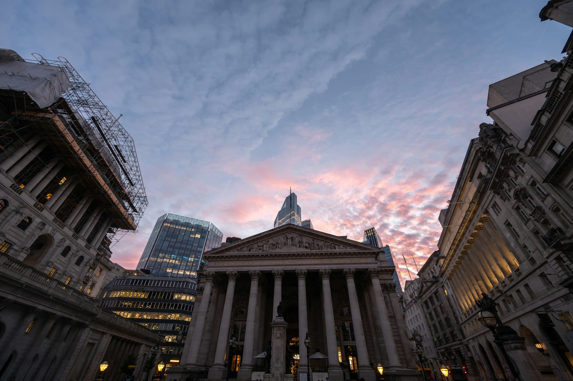 The columned Royal Exchange in London's financial district beneath a pink dusk sky
