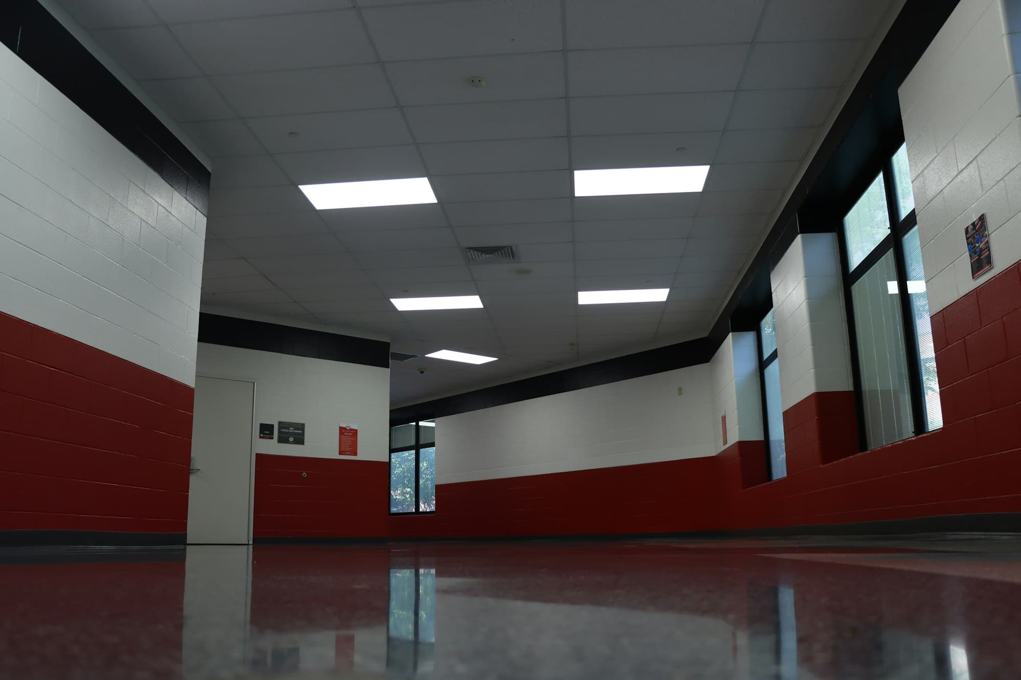 An empty school hallway with red and white walls and a reflective floor