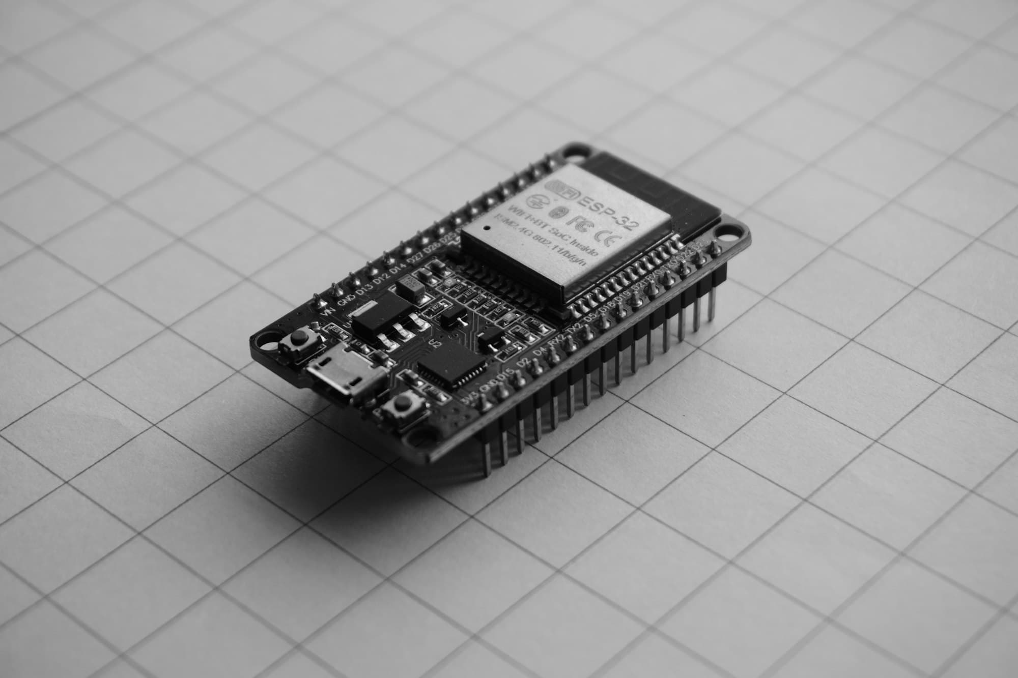 A black microcontroller development board on grid paper
