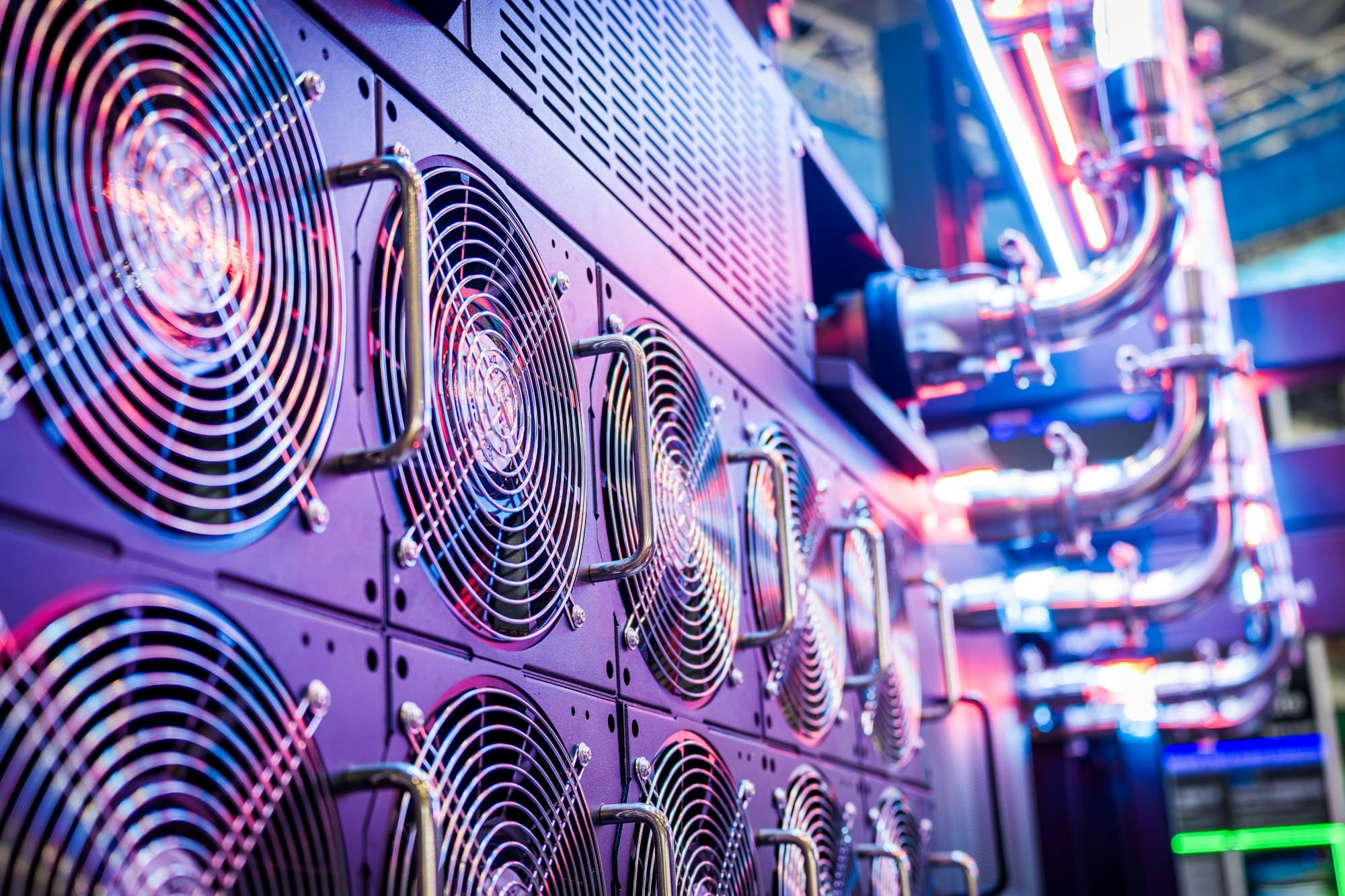 Rows of server cooling fans and metal pipes lit in purple and blue