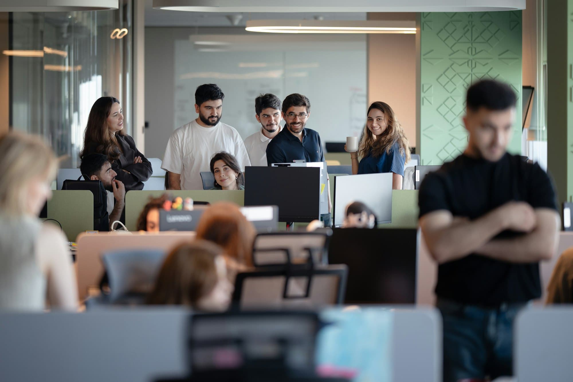 A team of people gathered around computers in a bright modern open-plan office