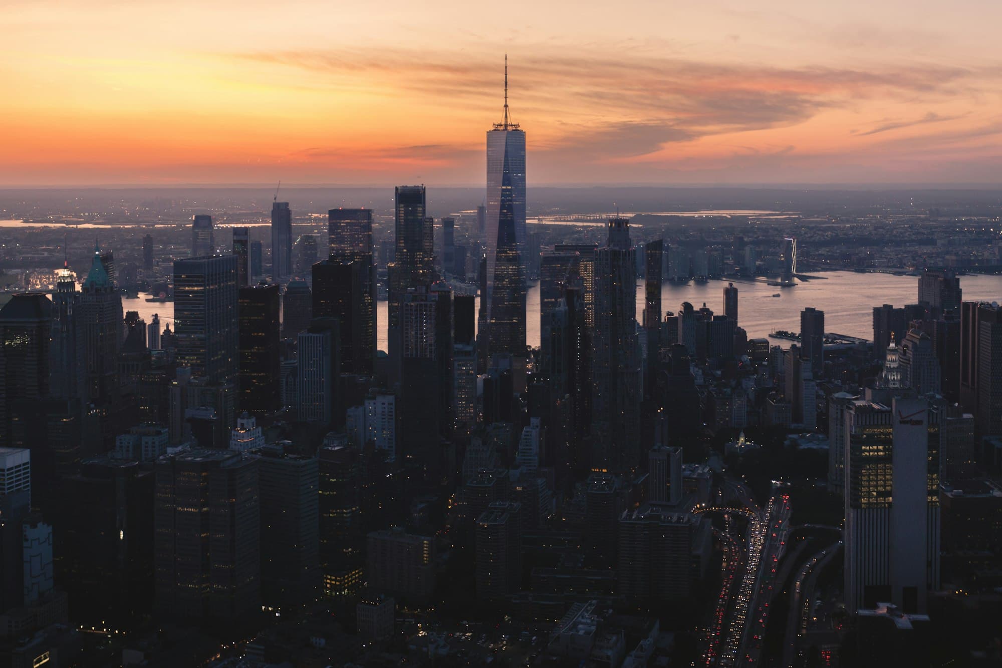 The Manhattan skyline at dusk with One World Trade Center rising above the city