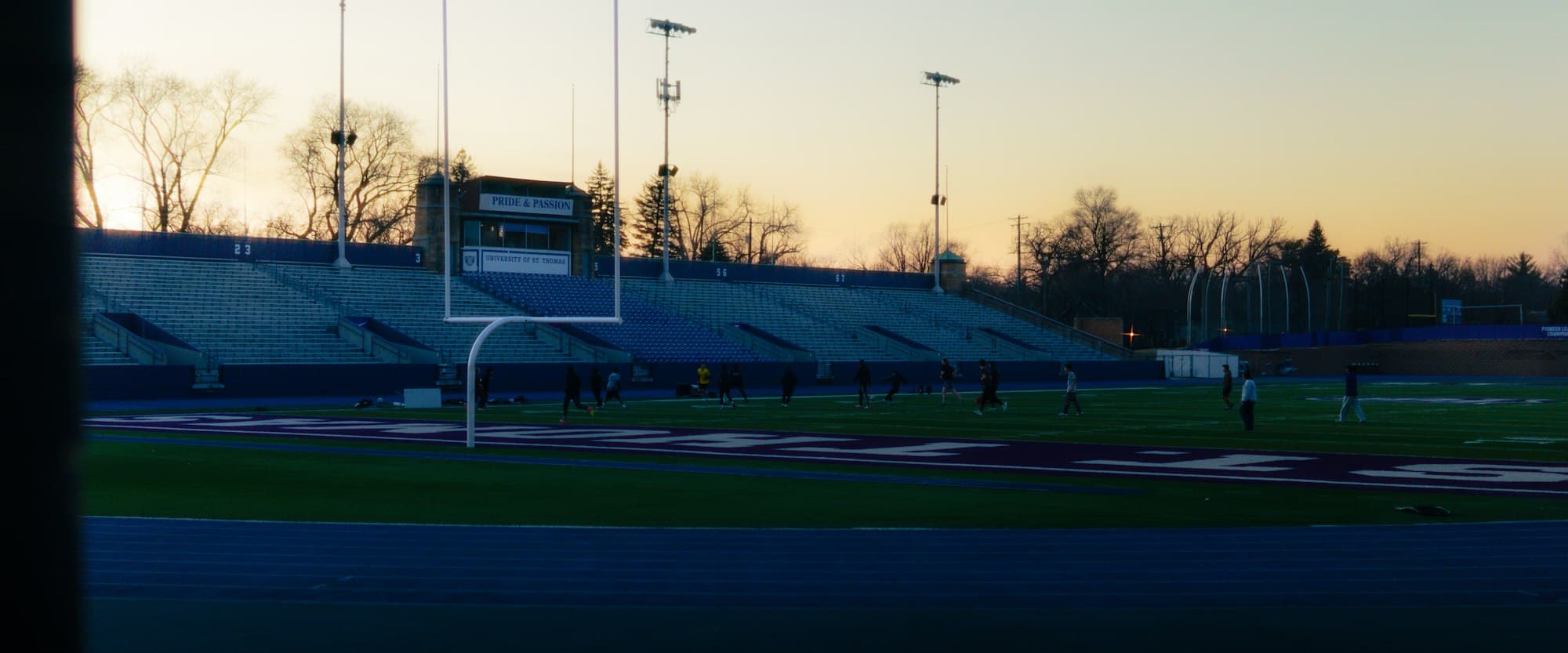 A football field with goalposts and bleachers at sunset
