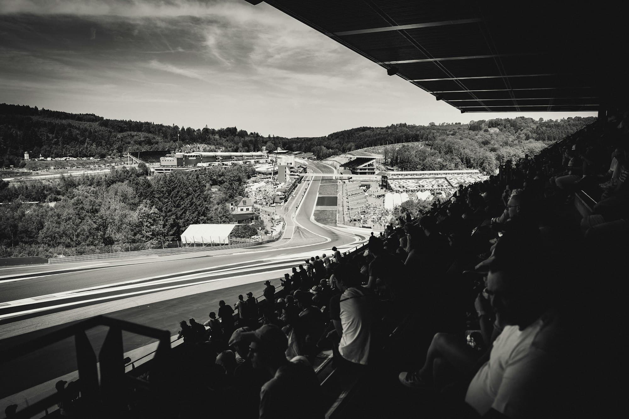 A black and white view of a winding race circuit through hills from a grandstand