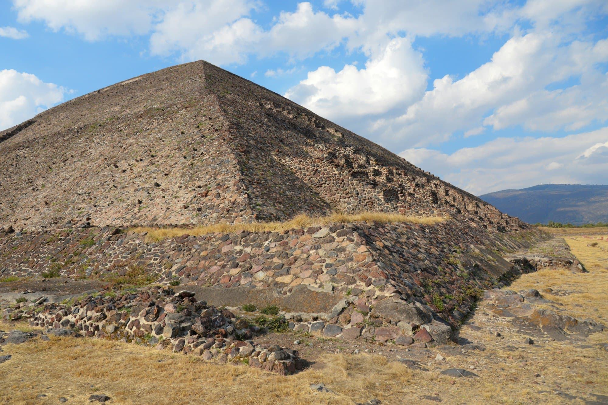 The weathered stone Pyramid of the Moon under a blue sky with clouds