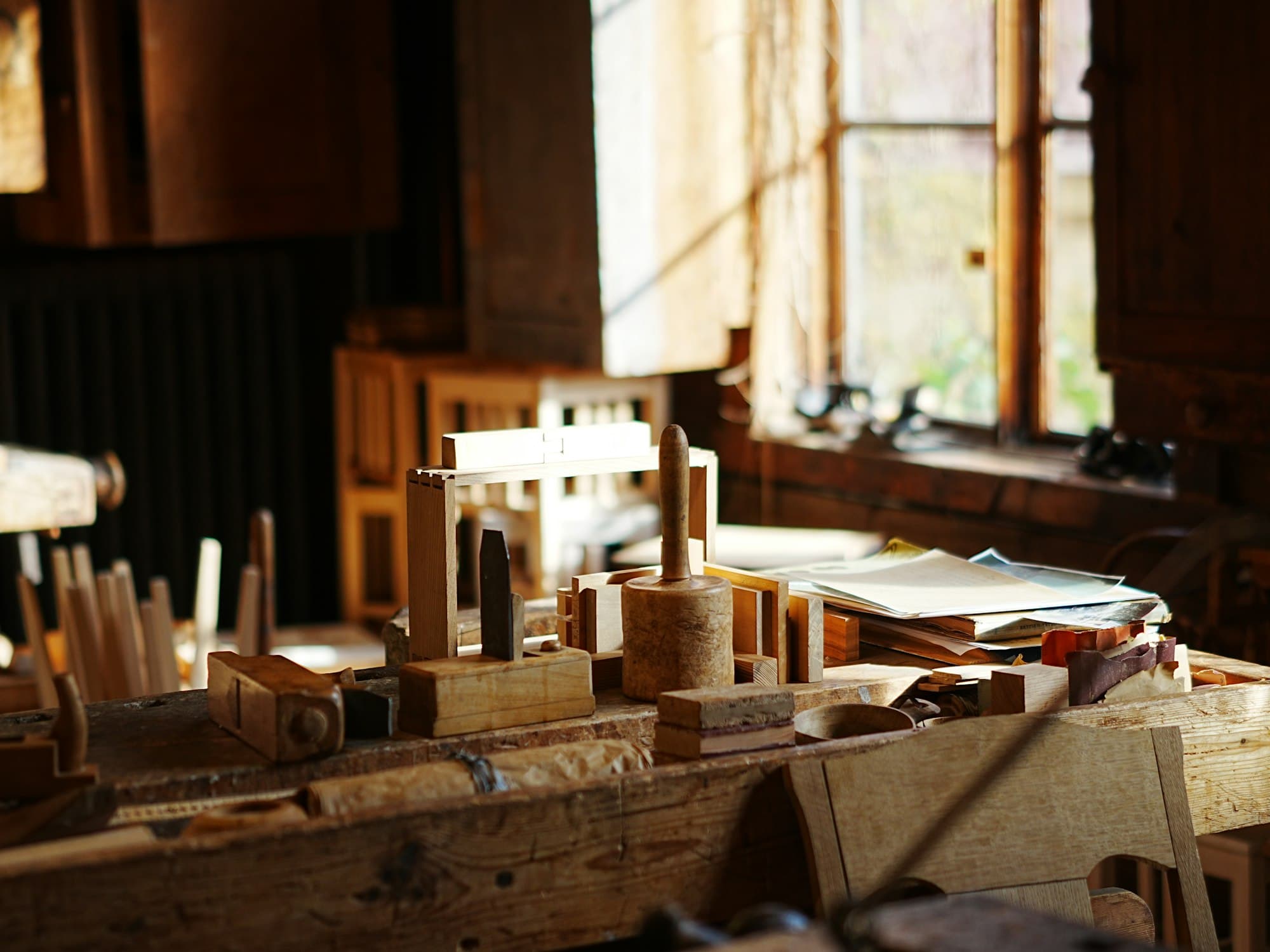 Wooden hand tools and mallets on a workbench in a sunlit workshop