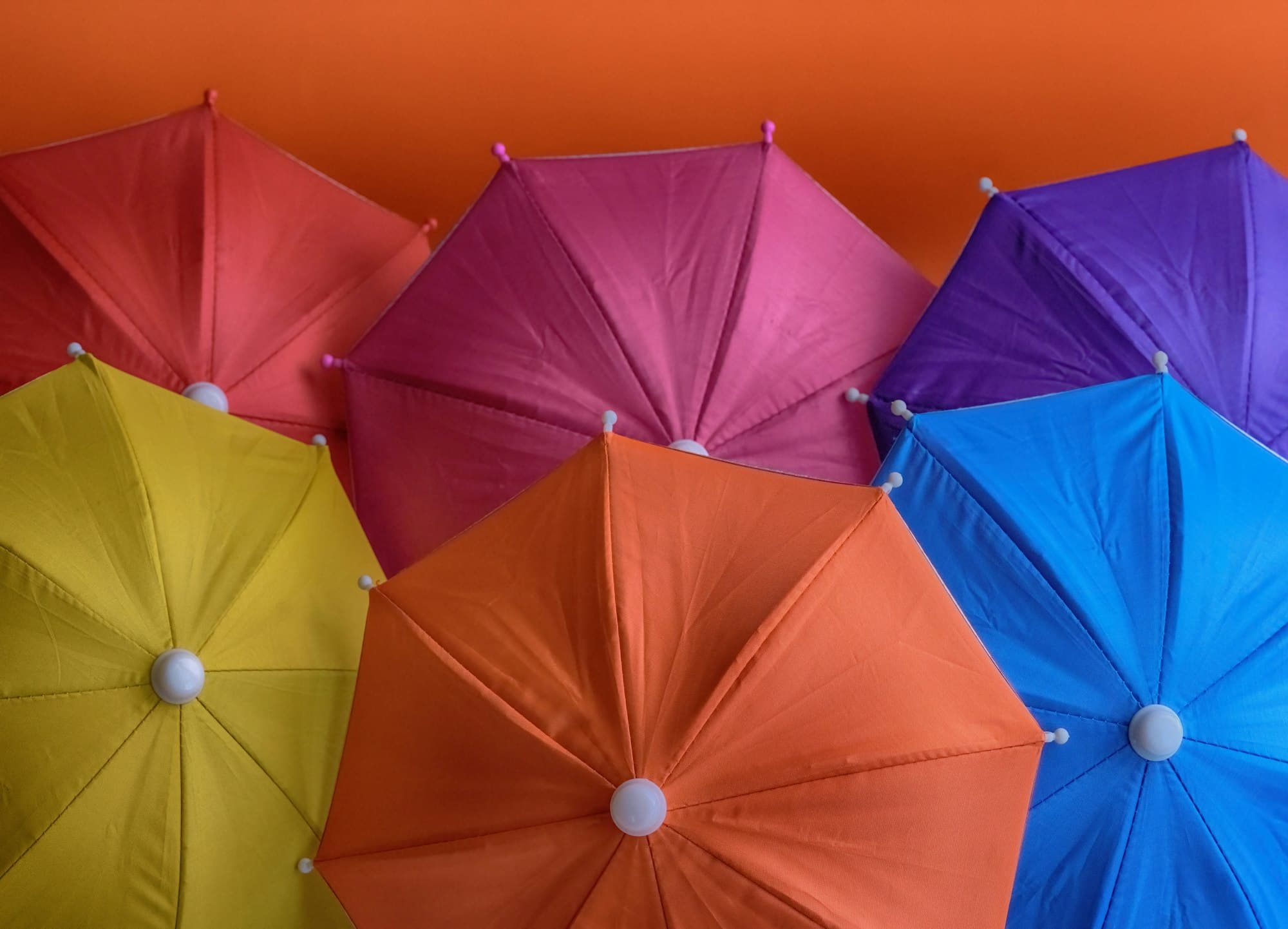 Six colorful umbrellas in yellow, orange, red, pink, purple and blue