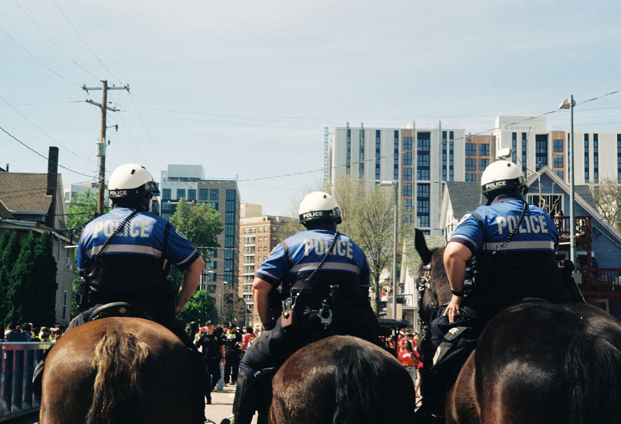 Three mounted police officers seen from behind patrol a city street