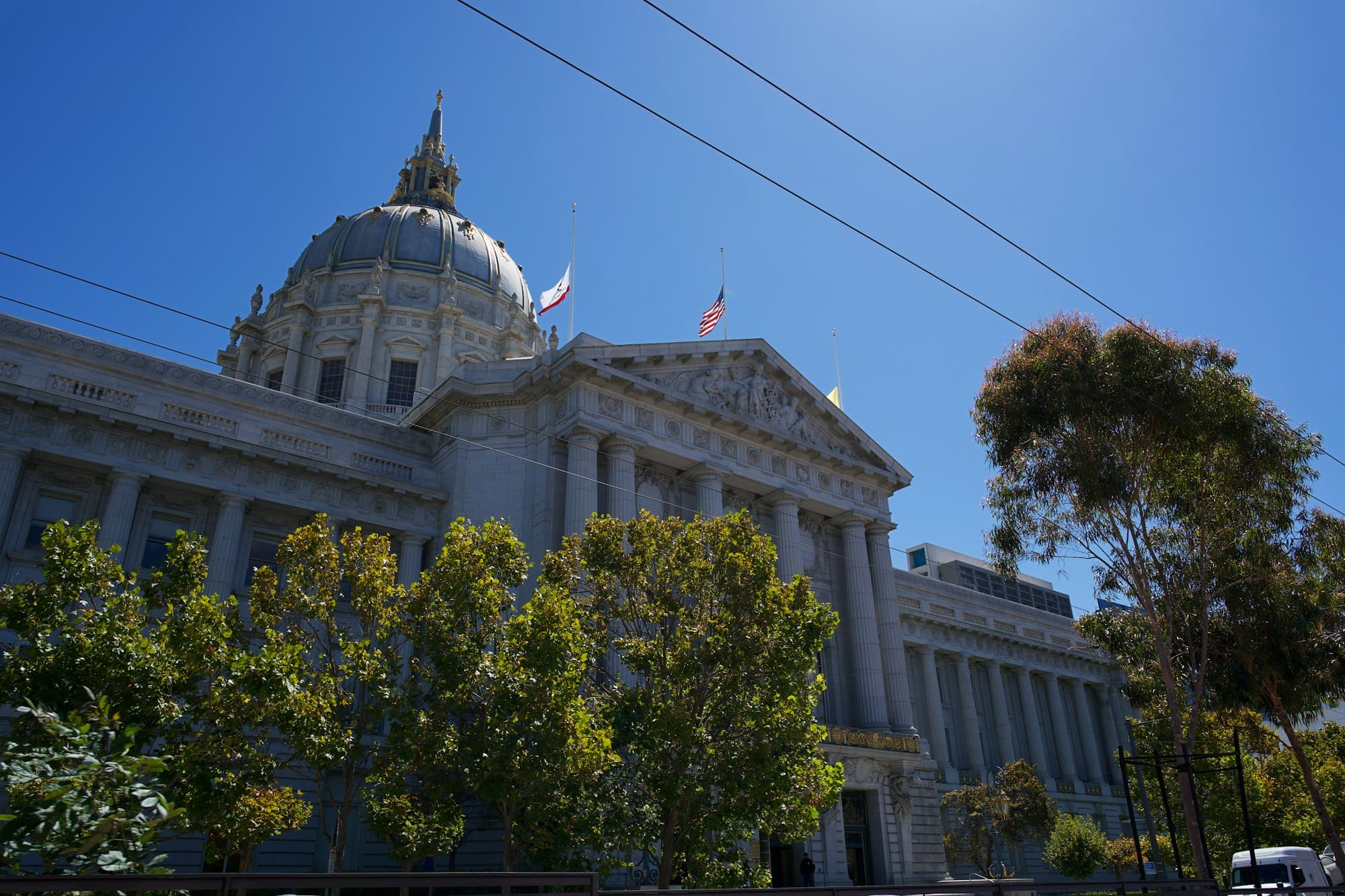 San Francisco City Hall with its dome and flags against a clear blue sky