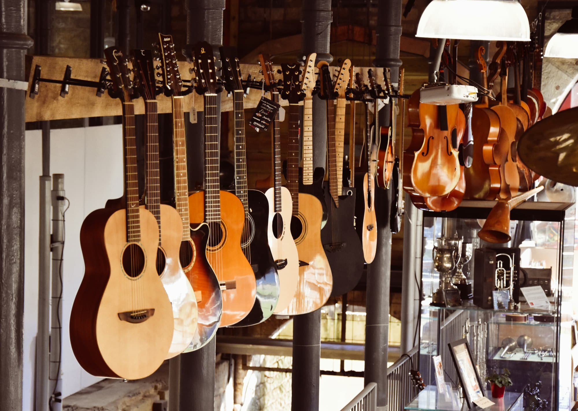 Rows of acoustic guitars and violins hanging in a vintage instrument shop