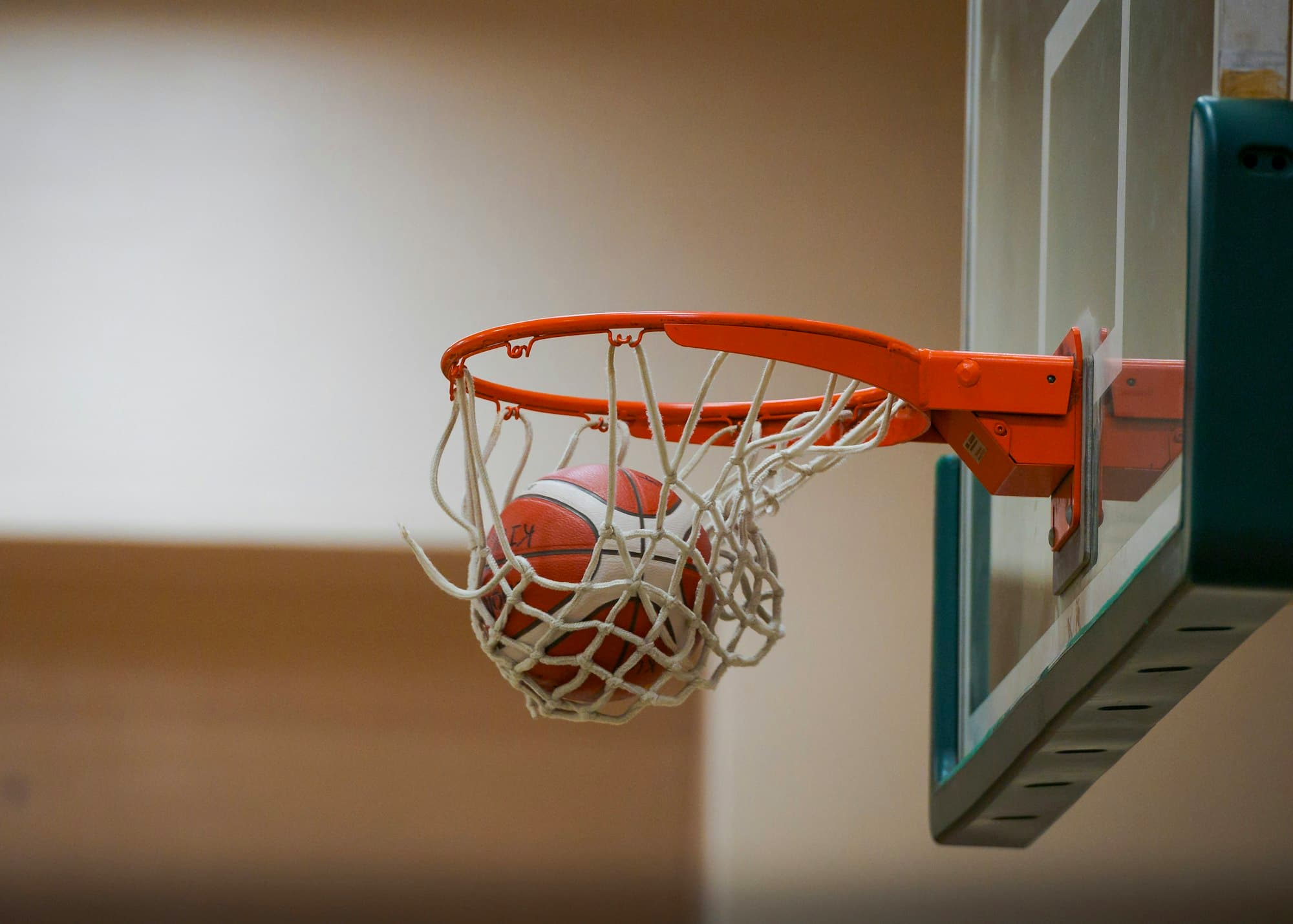 A basketball drops through the net of an indoor hoop