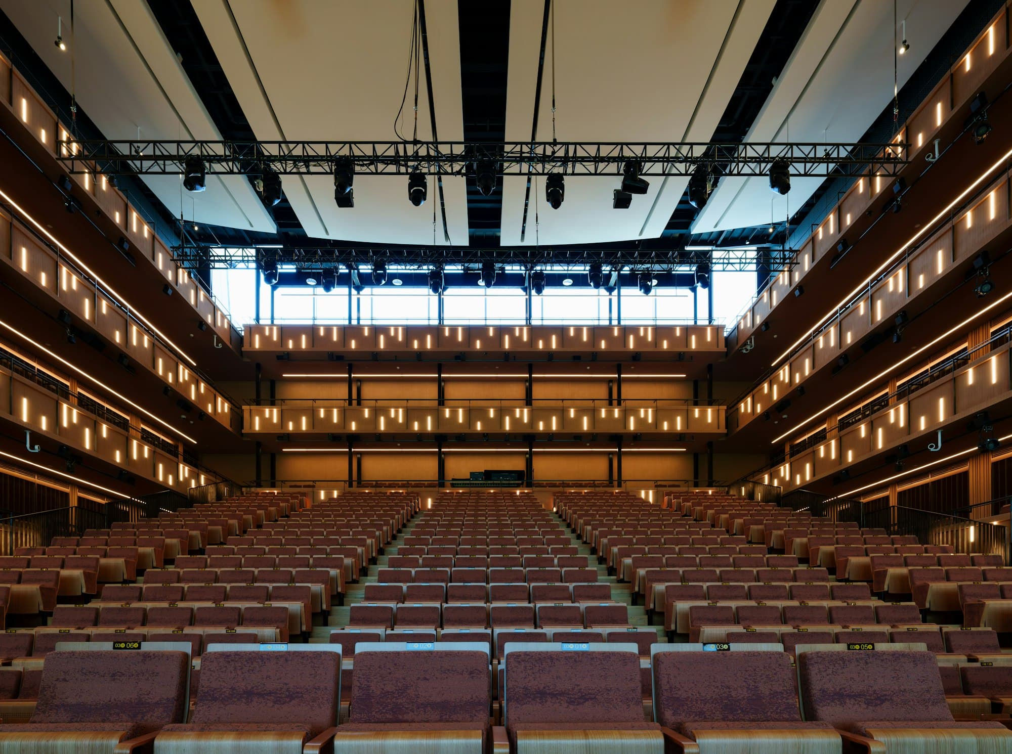 Rows of empty theatre seats facing a stage with overhead lighting rigs