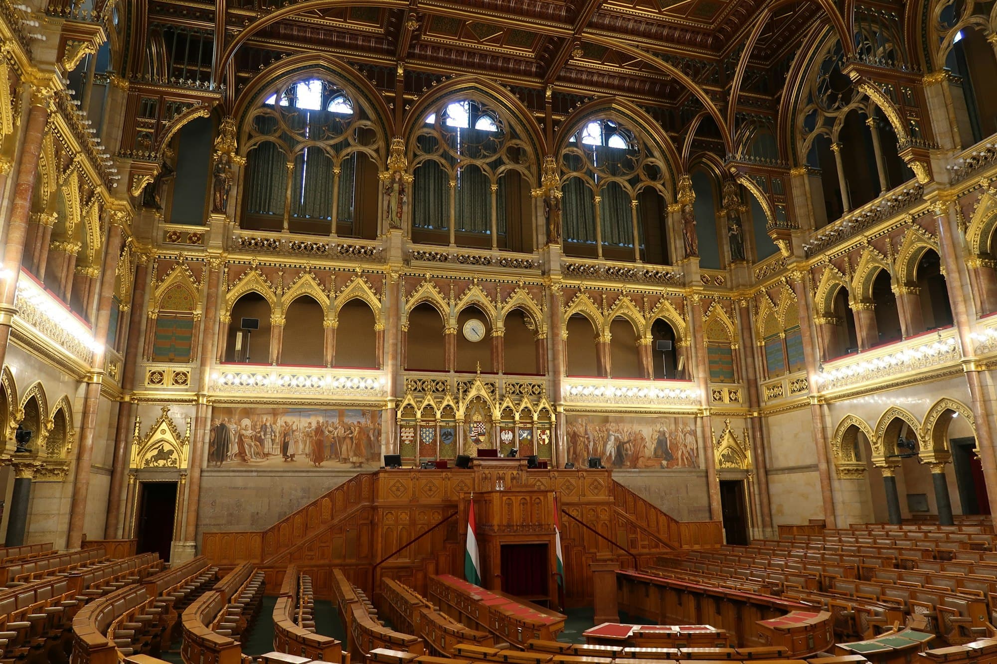 The ornate gilded and wood-panelled interior of the Hungarian parliamentary chamber with empty benches