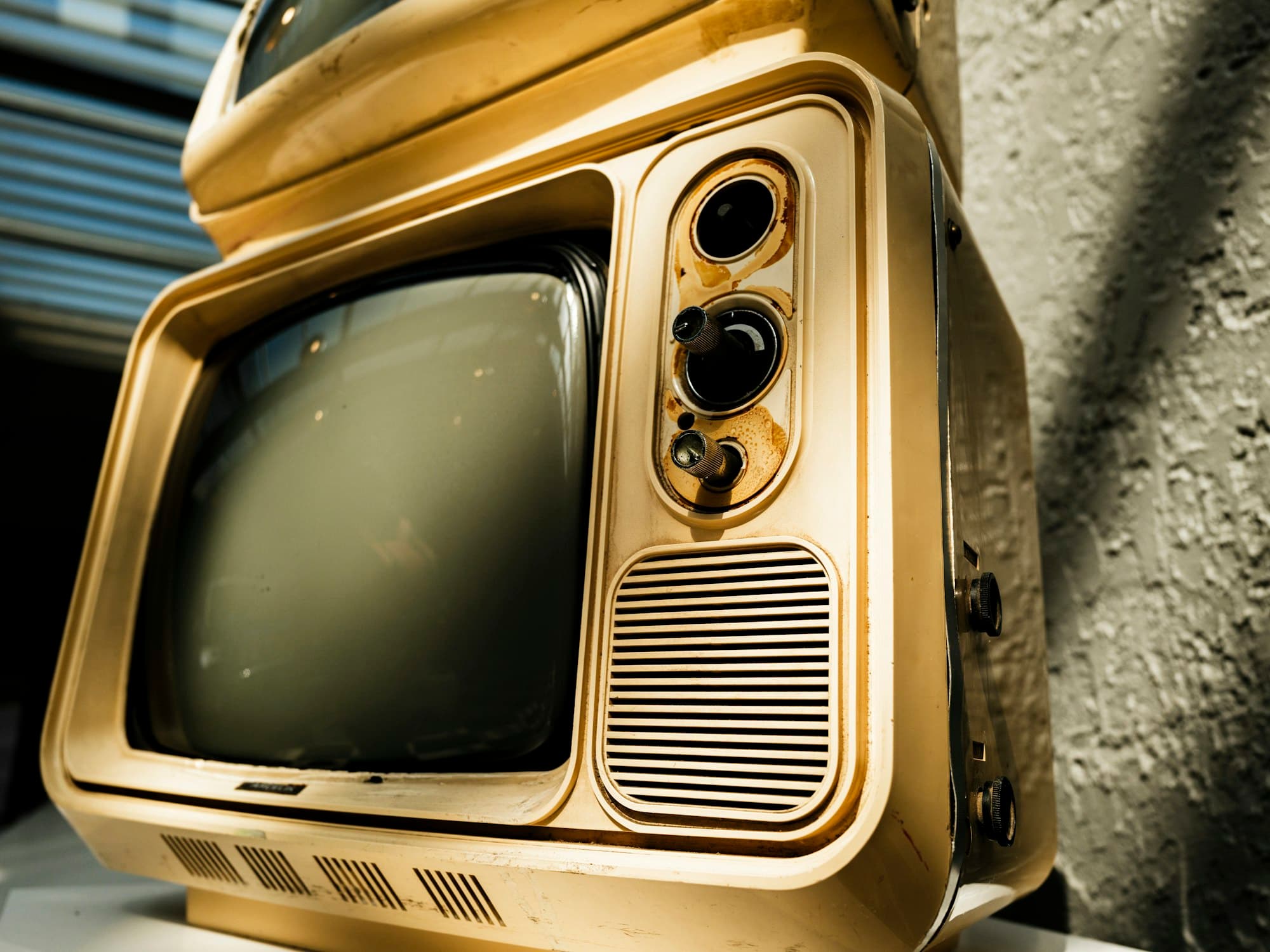 A vintage television with a cream plastic casing and knobs