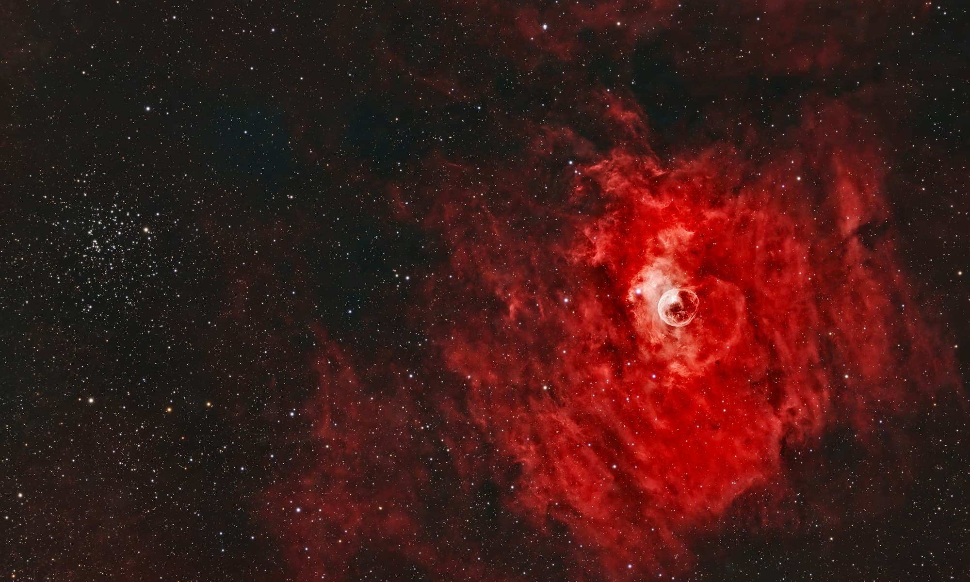 The Bubble Nebula glowing red among scattered stars in deep space
