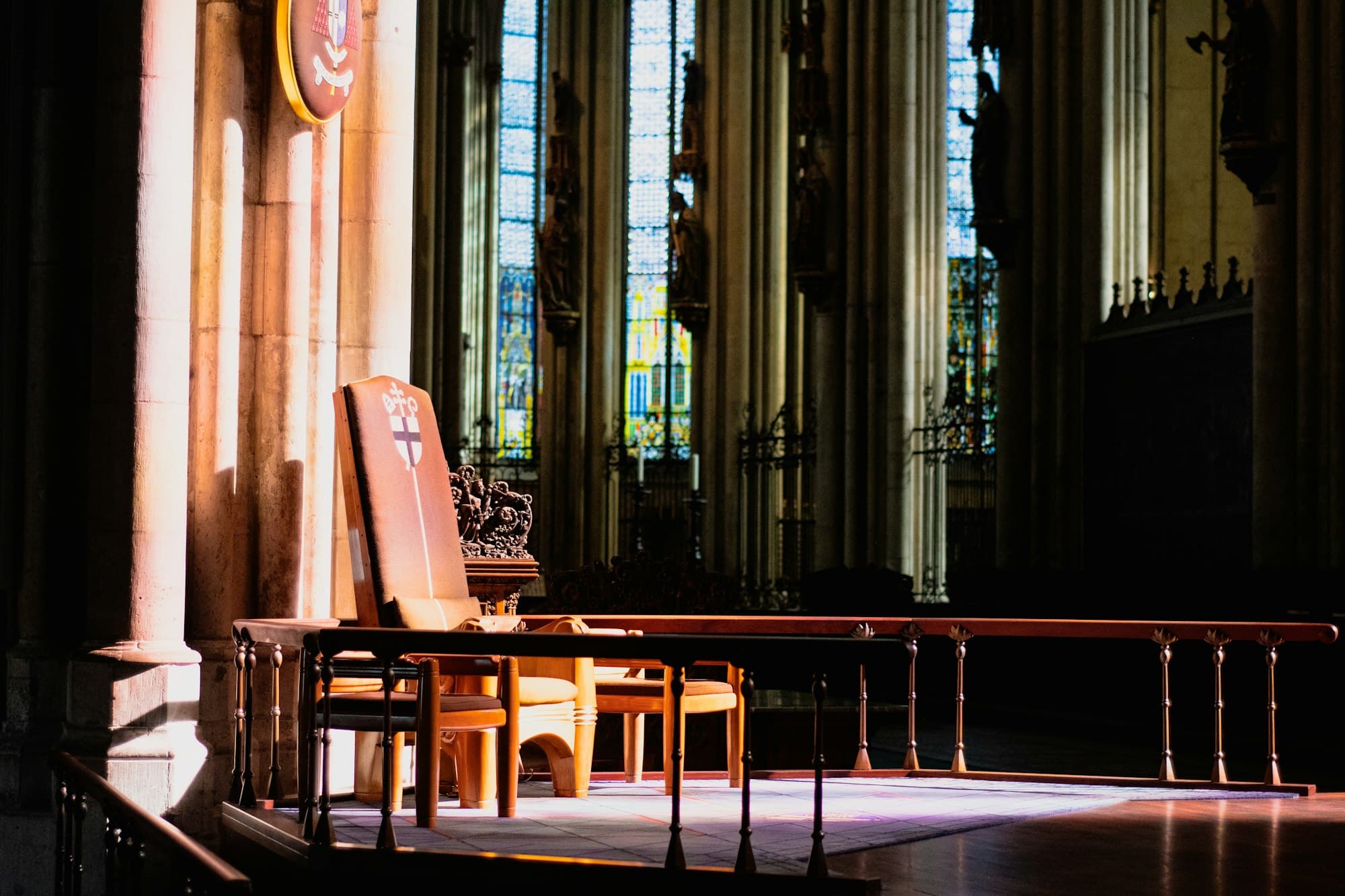 A wooden chair on a raised platform in a cathedral lit by shafts of sunlight
