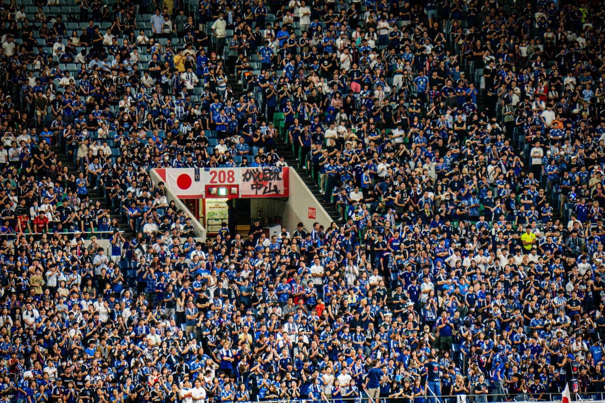 A dense crowd of fans fills the stadium seating