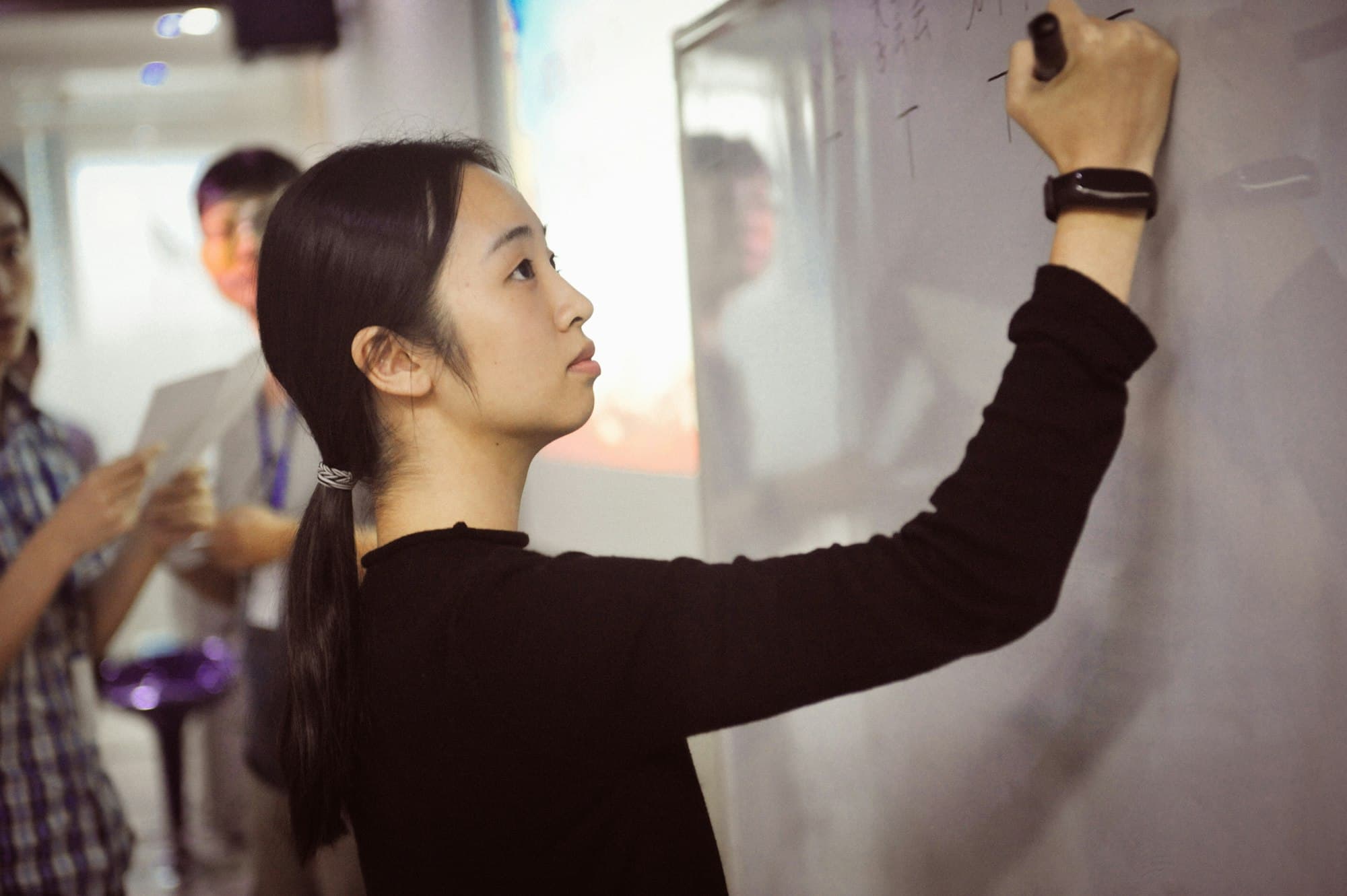 A young woman writes on a whiteboard