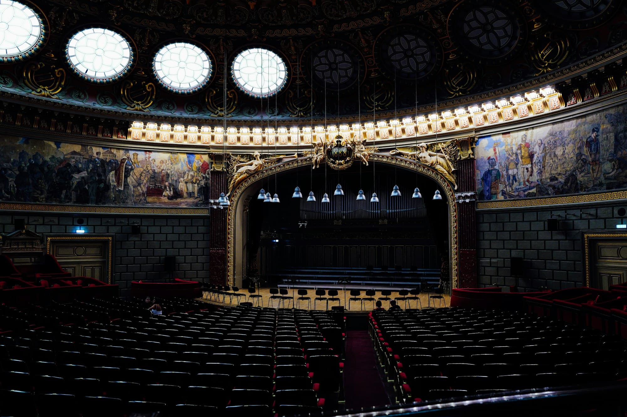 Rows of empty seats facing a stage in an ornate theater hall