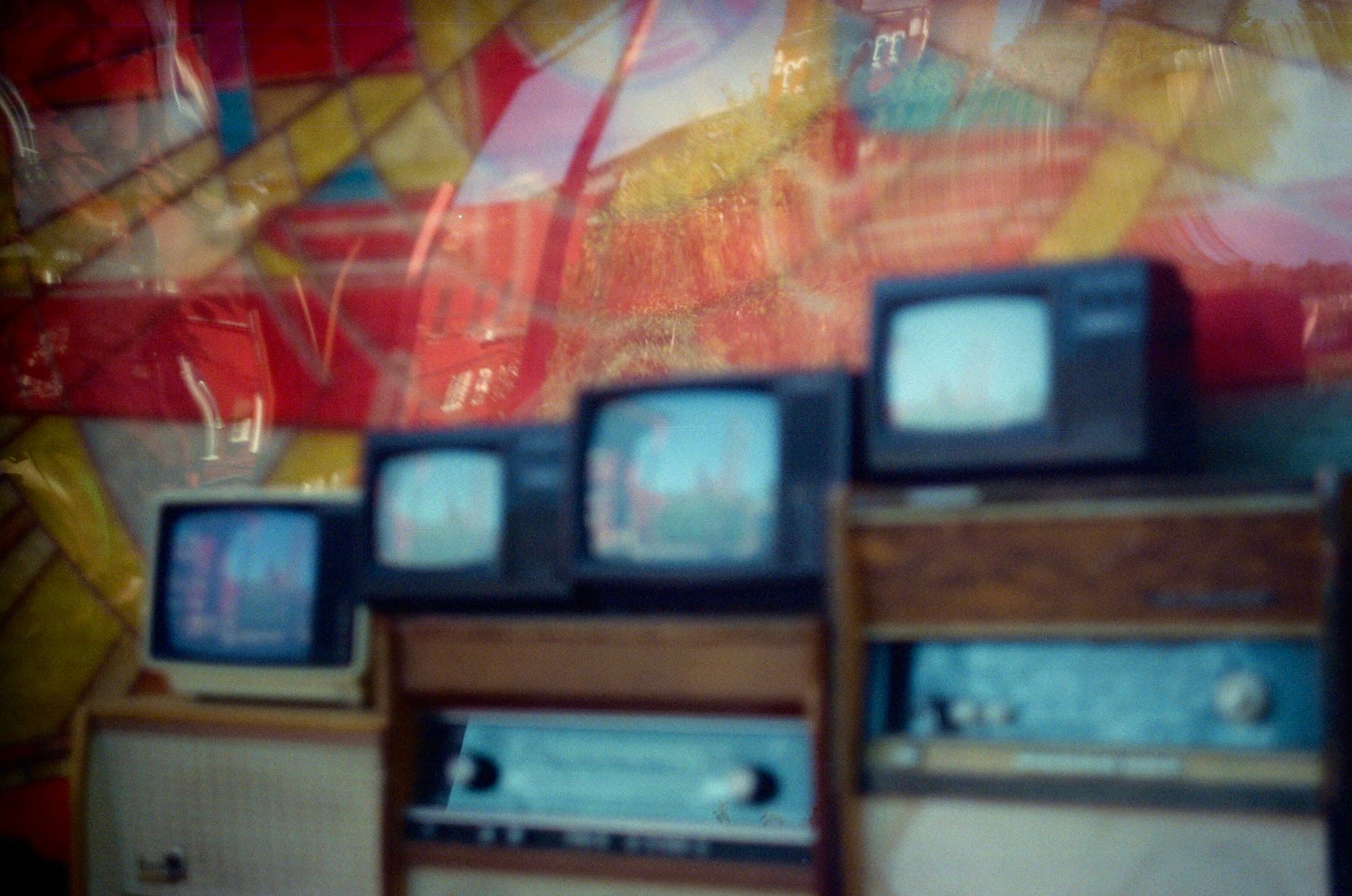 Vintage television sets on wooden cabinets against a colorful backdrop