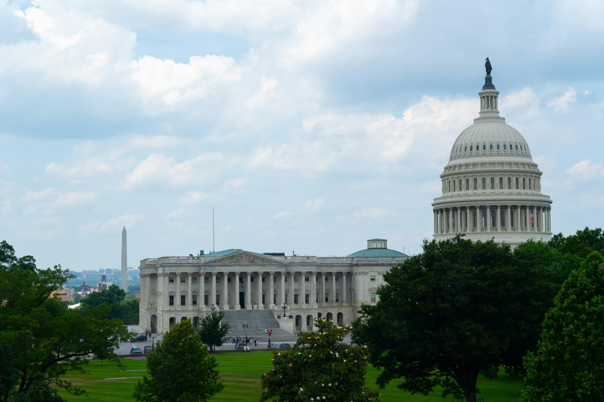 The US Capitol dome with the Washington Monument in the distance across green lawns